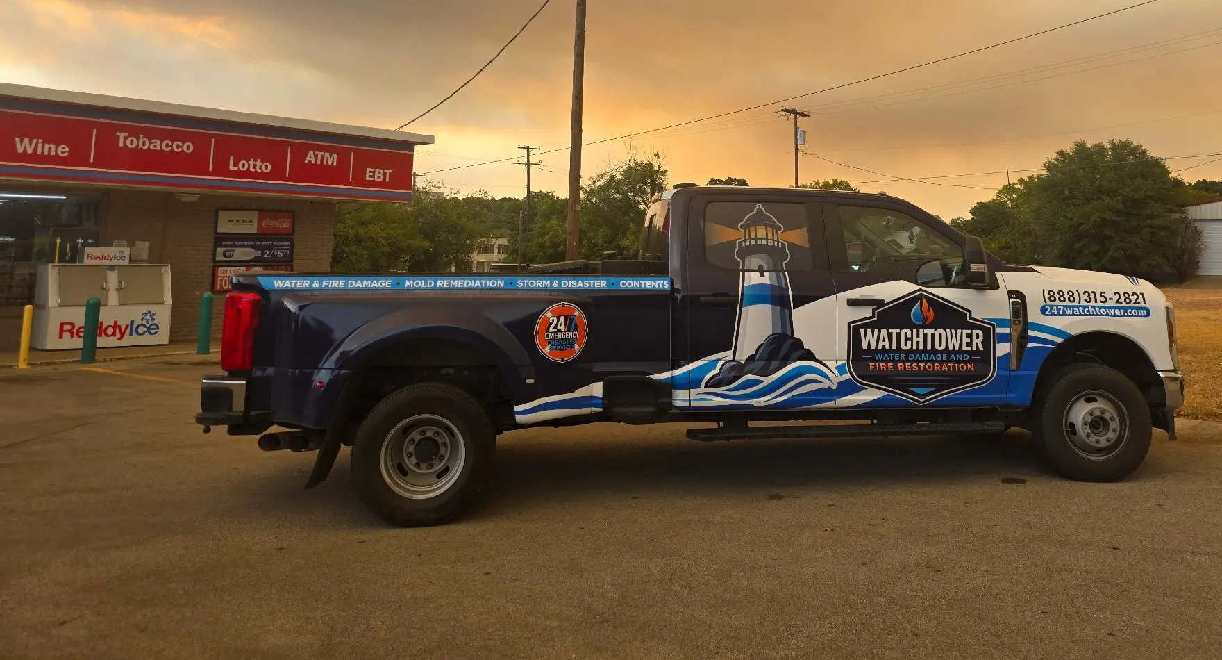 Wrapped service pickup truck at a gas station under an orange smoky sky, water and fire damage restoration